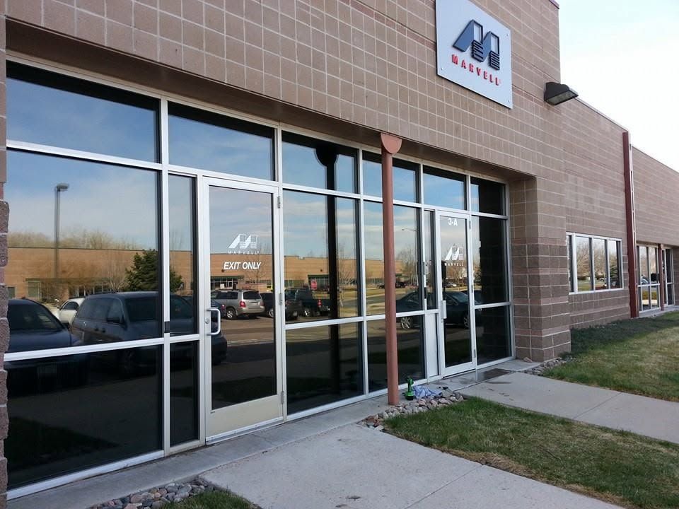 Exterior of a storefront with large glass windows, brick facade, and a sidewalk leading to the entrance