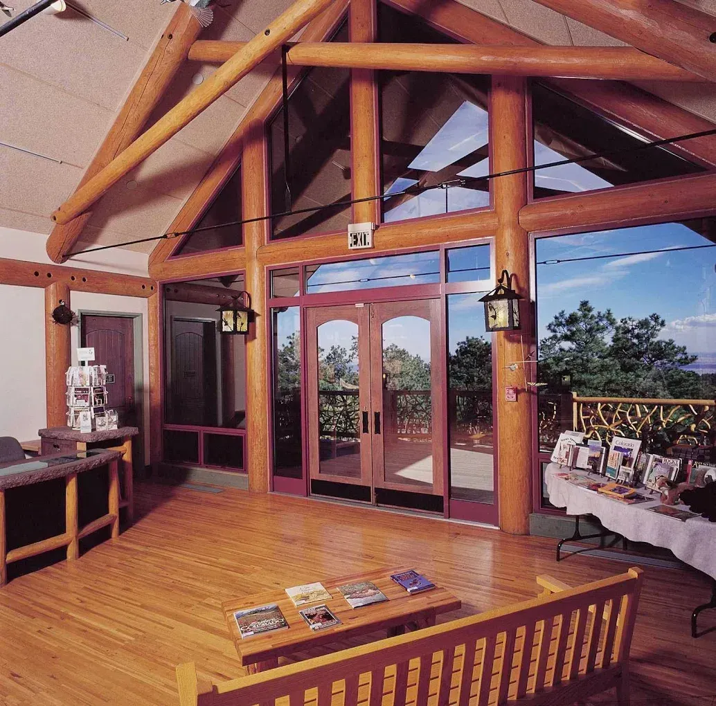 Rustic lodge interior with wood beams, glass doors, and a mountain view