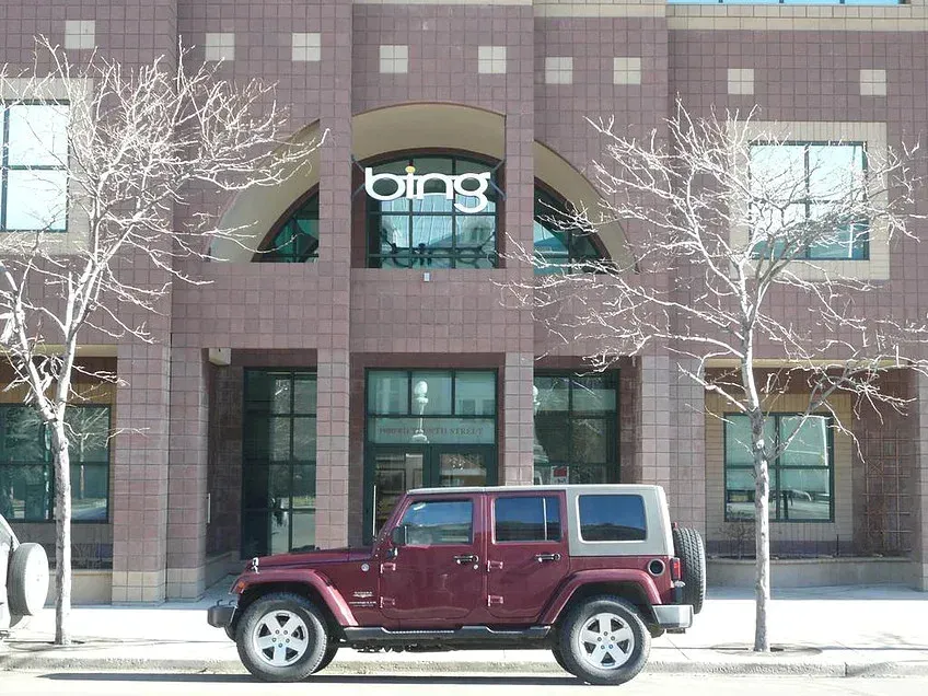 Maroon Jeep parked in front of a building with a Bing sign and leafless trees