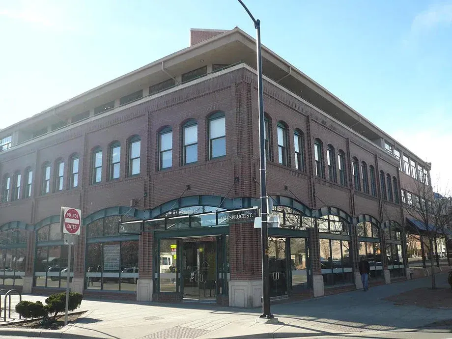Brick corner building with large windows and storefronts on a sunny street corner
