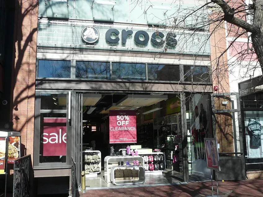 Storefront with sale signs and open entrance, likely a cosmetics shop named “CROCS” on a city street