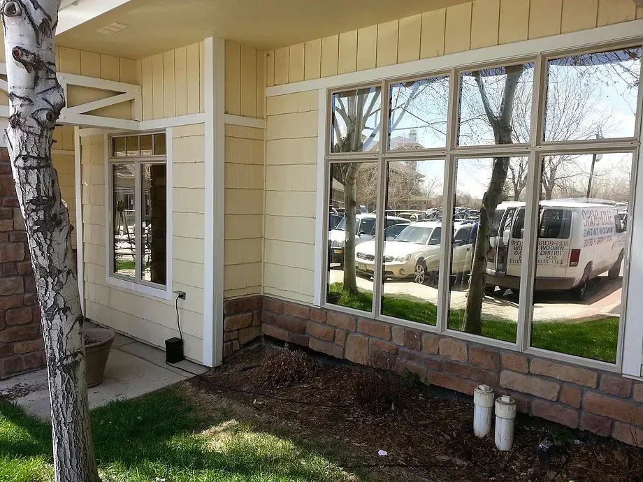 Covered house entrance with white-trimmed windows, brick base, and parked vehicles visible outside.