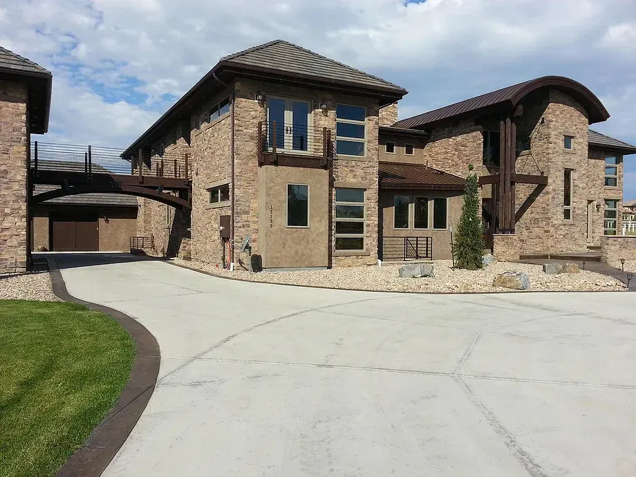 Large stone residential buildings with a curved concrete driveway and a small patch of grass.