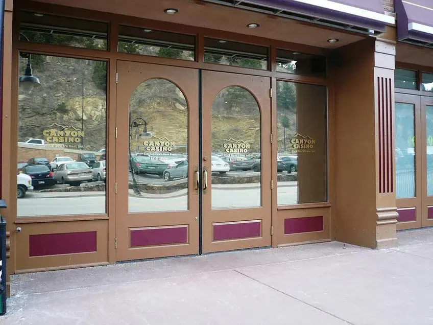 Brown storefront glass doors with arched window panels and purple lower panels at a sidewalk entrance