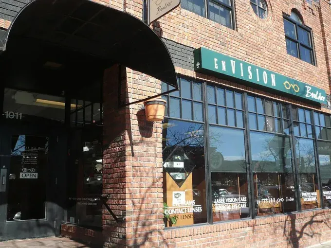 Brick storefront with large windows and green sign reading “Division,” in bright sunlight.