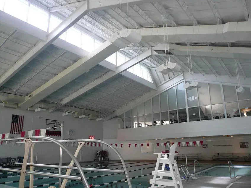 Indoor swimming pool with lane lines, diving boards, and a high white ceiling
