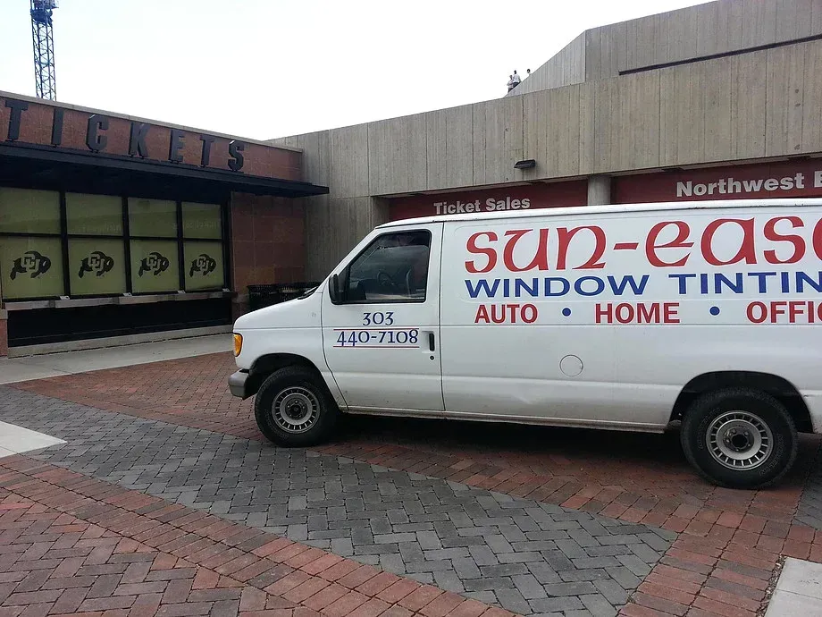 White Sun-Ease Window Tinting van parked outside a building with brick walkway.