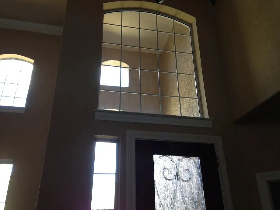 Front door with frosted glass and arched windows in a dimly lit interior foyer