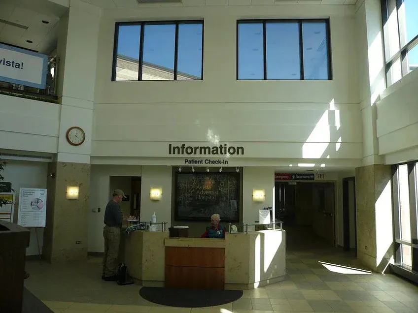 Bright lobby with an information desk, tall windows, and people waiting nearby.