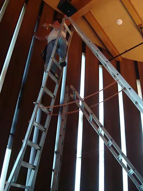 Person on ladder inspecting ceiling beams in a wooden interior