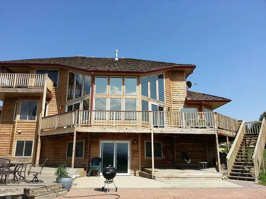 Wooden beachfront house with balconies and patio under a clear blue sky