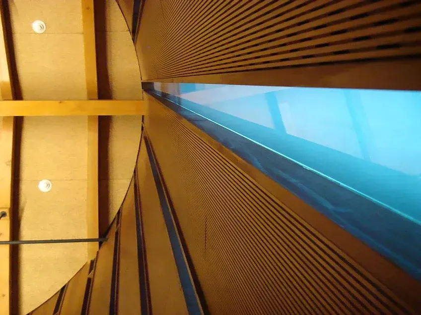 Abstract interior with wood slats and a bright blue skylight viewed from a low angle