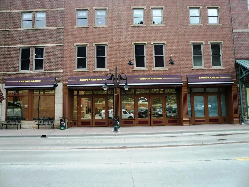 Brick storefronts with large windows along a city street, shown from across the road