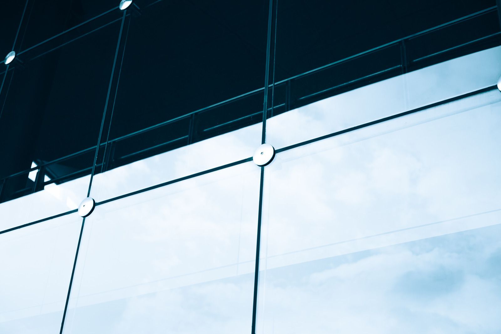 Abstract view of glass building facade with blue sky reflections and metal support lines