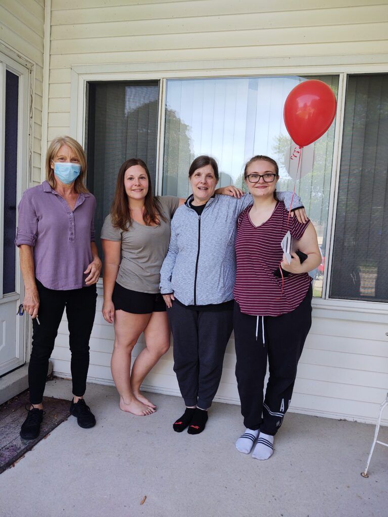 Young women pose for a picture with a red balloon.