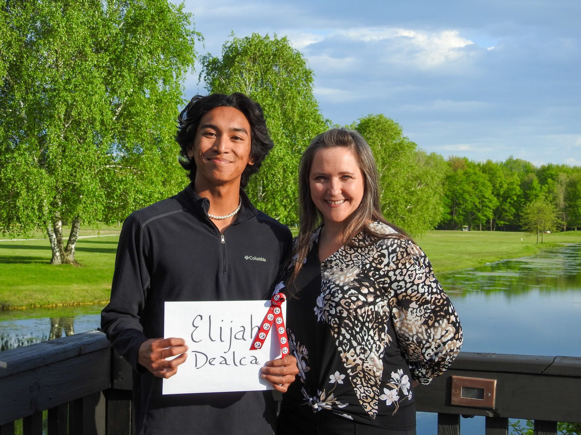 A young man holding a sign with his name on it.