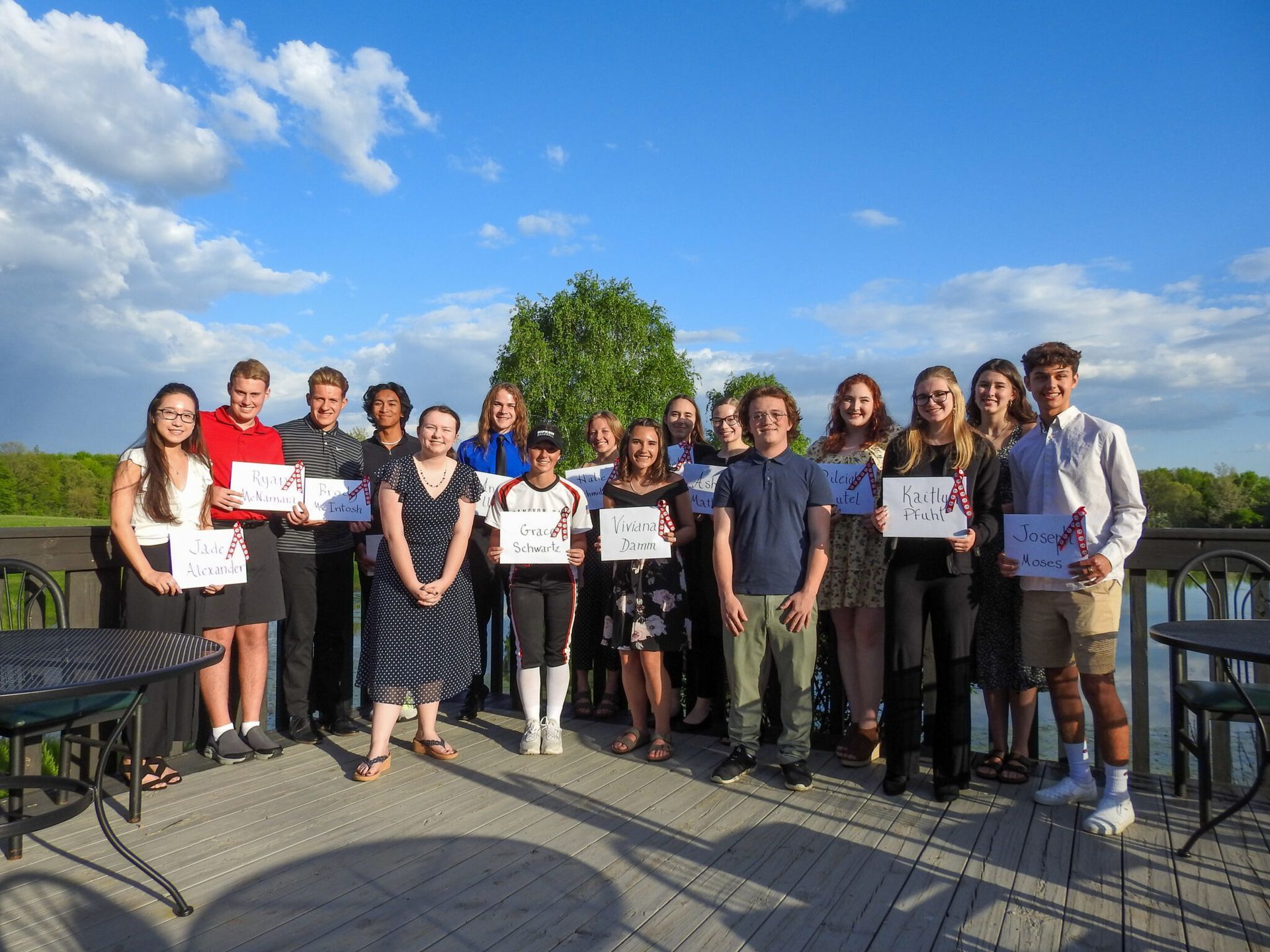A group of graduates holding signs with their names on them.