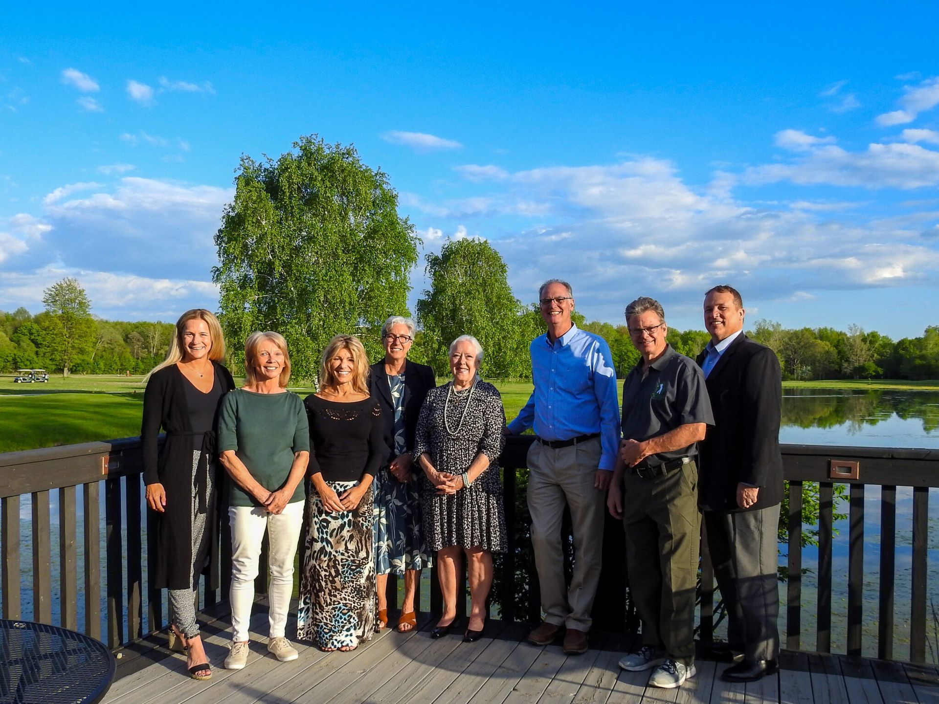 A group of people standing on a deck overlooking a lake.