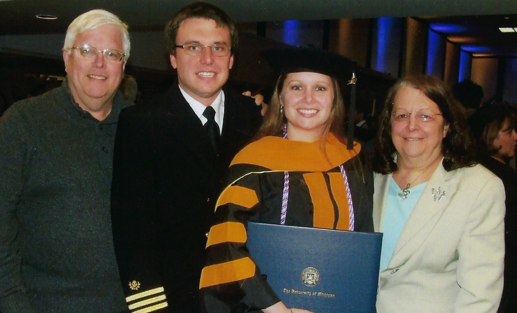 A woman in a graduation cap and gown is holding a diploma.