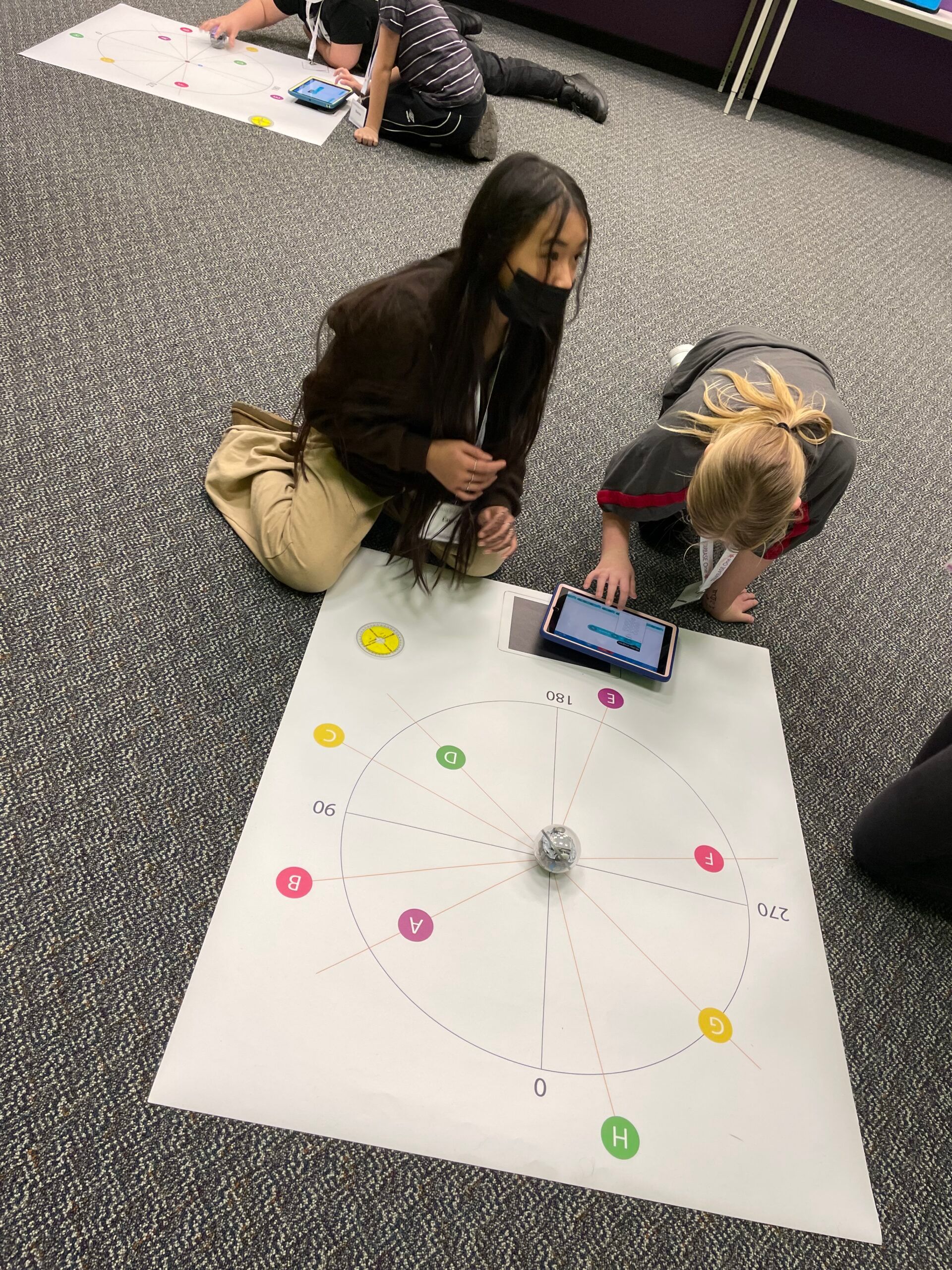 A group of children sitting in front of a poster board.