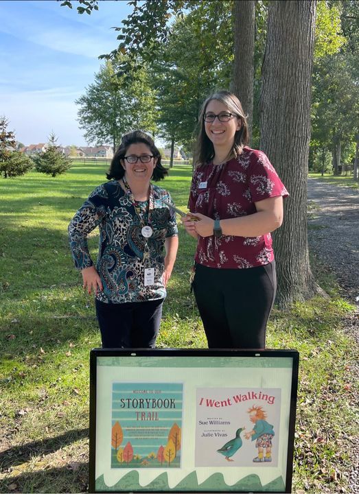 Two women standing outside in front of a display of children's books.