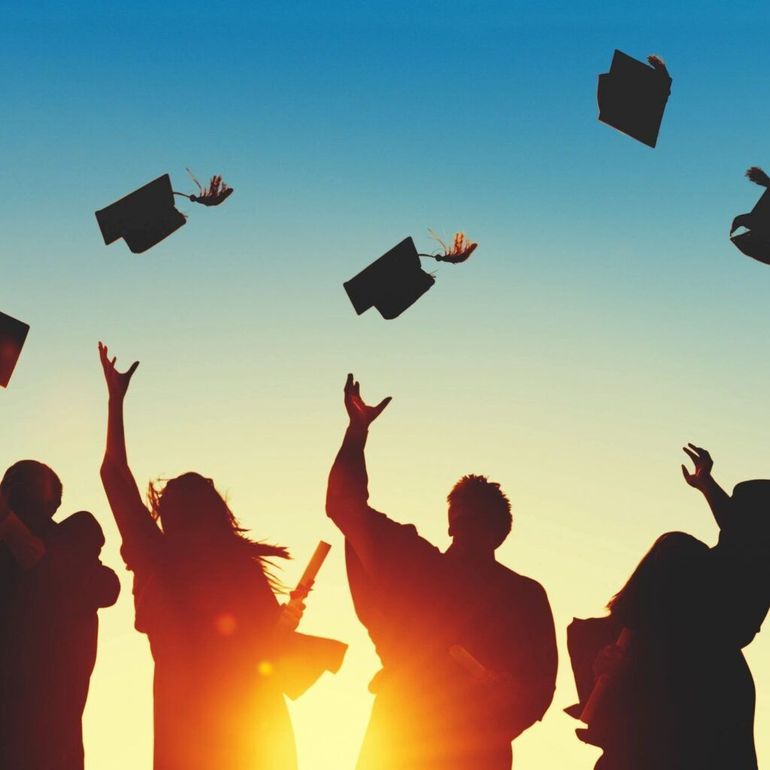 A group of graduates are throwing their caps in the air.