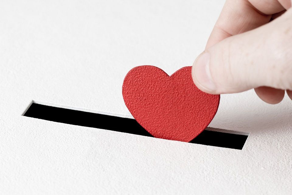 A person putting a red heart into a box.
