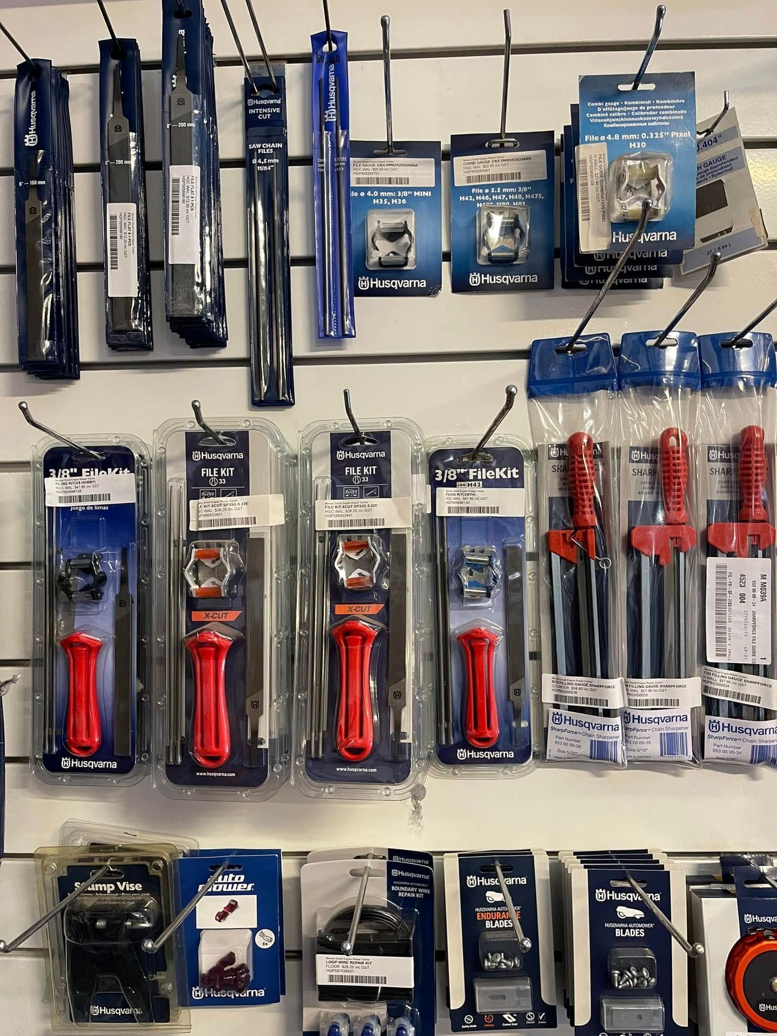 Assorted hand tools in blue and red packaging displayed on a store pegboard wall.