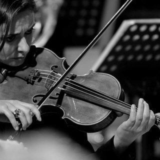 Donna che suona il violino concentrata; bianco e nero.