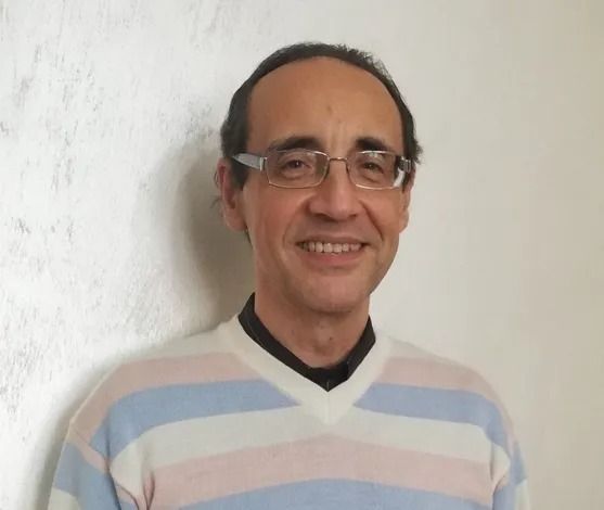 L'uomo che indossa occhiali e maglione a righe sorride.