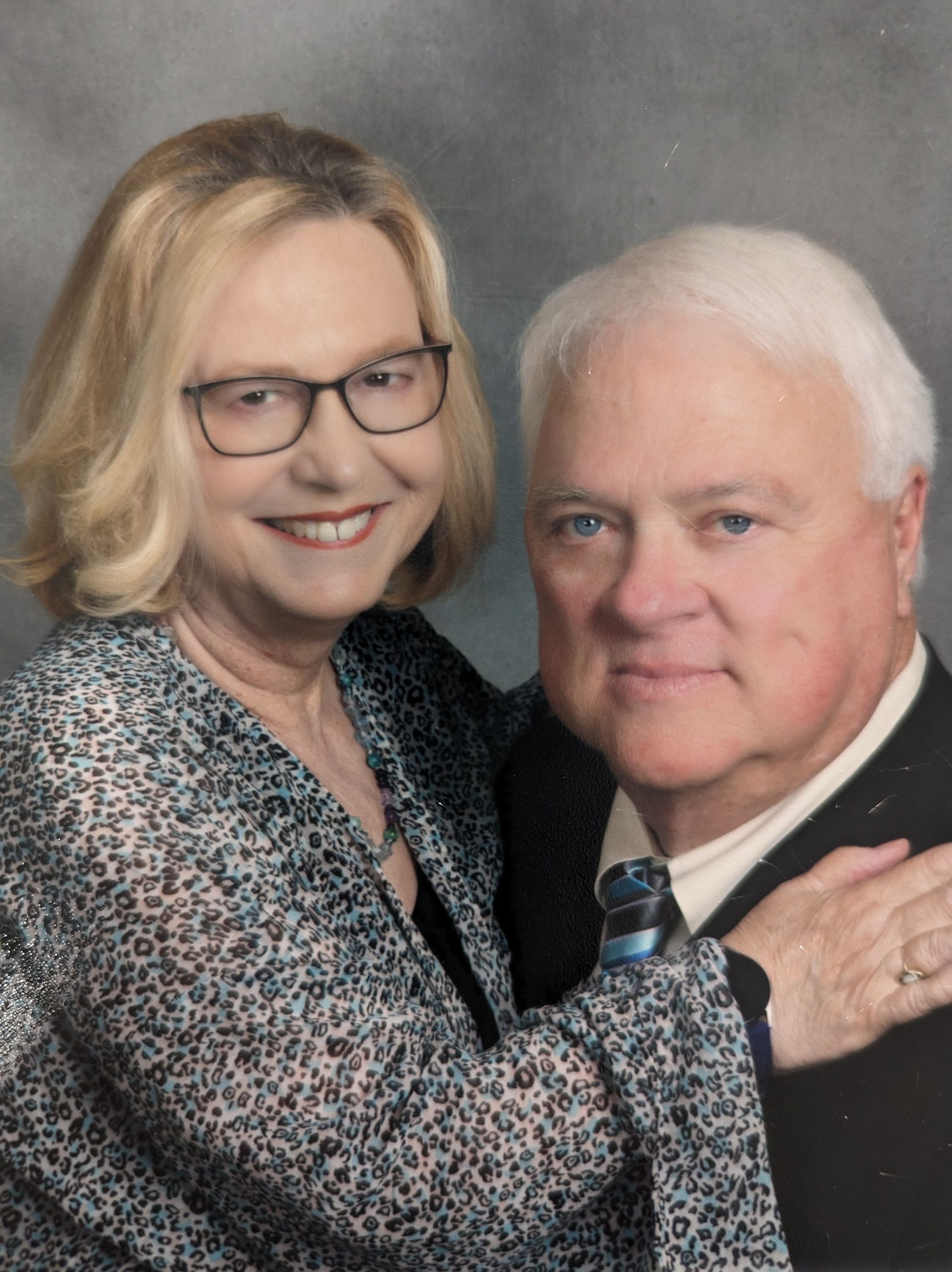 Smiling couple posed together against a gray studio backdrop