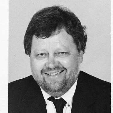 Black-and-white portrait of a smiling man in a suit and tie