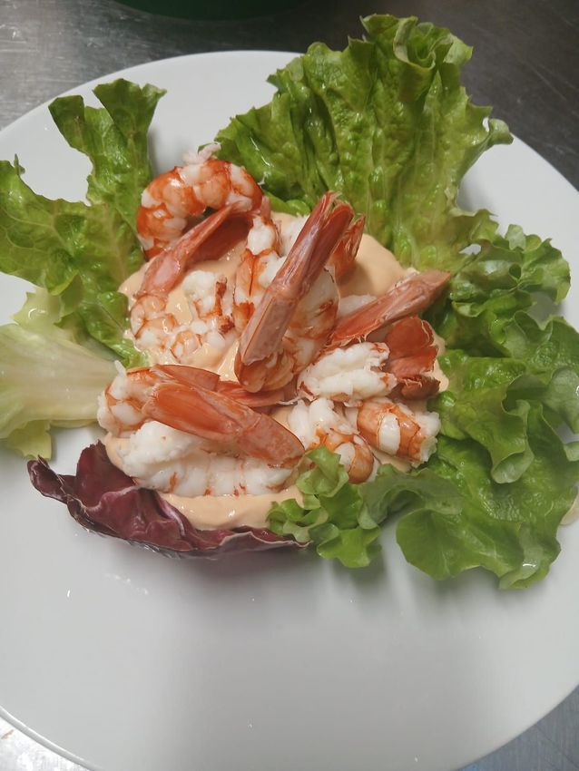 Insalata di gamberetti su un letto di lattuga in una ciotola bianca su un piatto