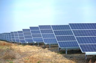 Row of solar panels in a dry field under a clear blue sky