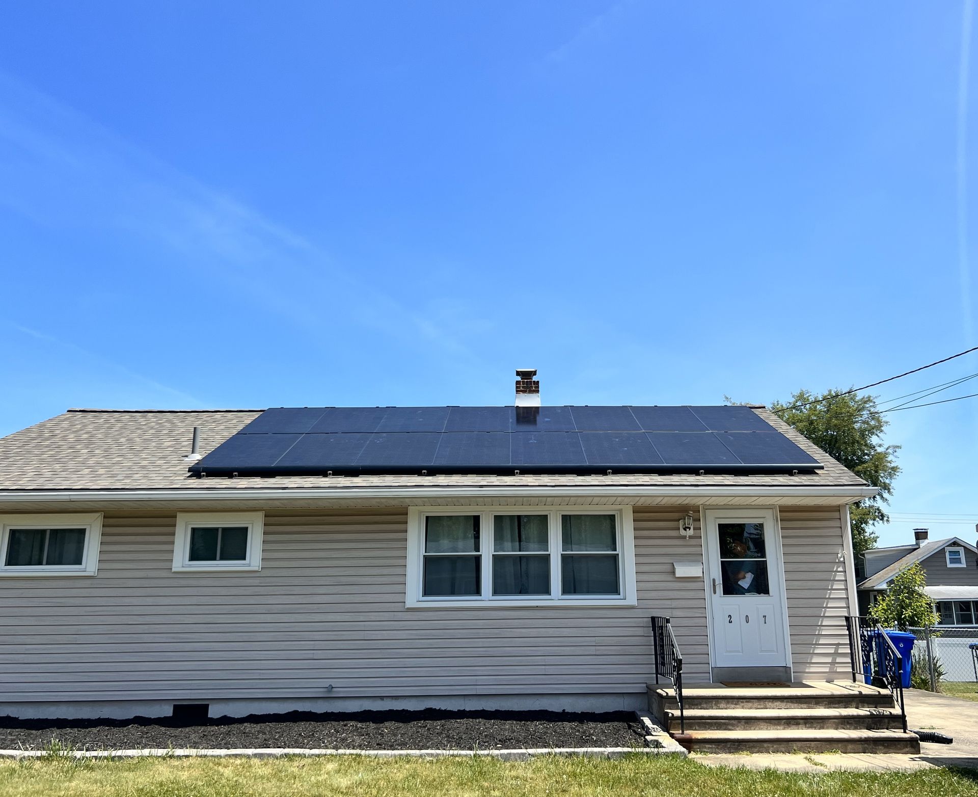 Single-story house with rooftop solar panels under a clear blue sky