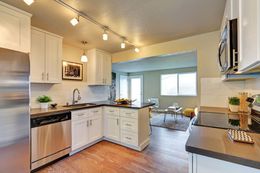 Bright modern kitchen with white cabinets, stainless appliances, and a breakfast nook beside a large window