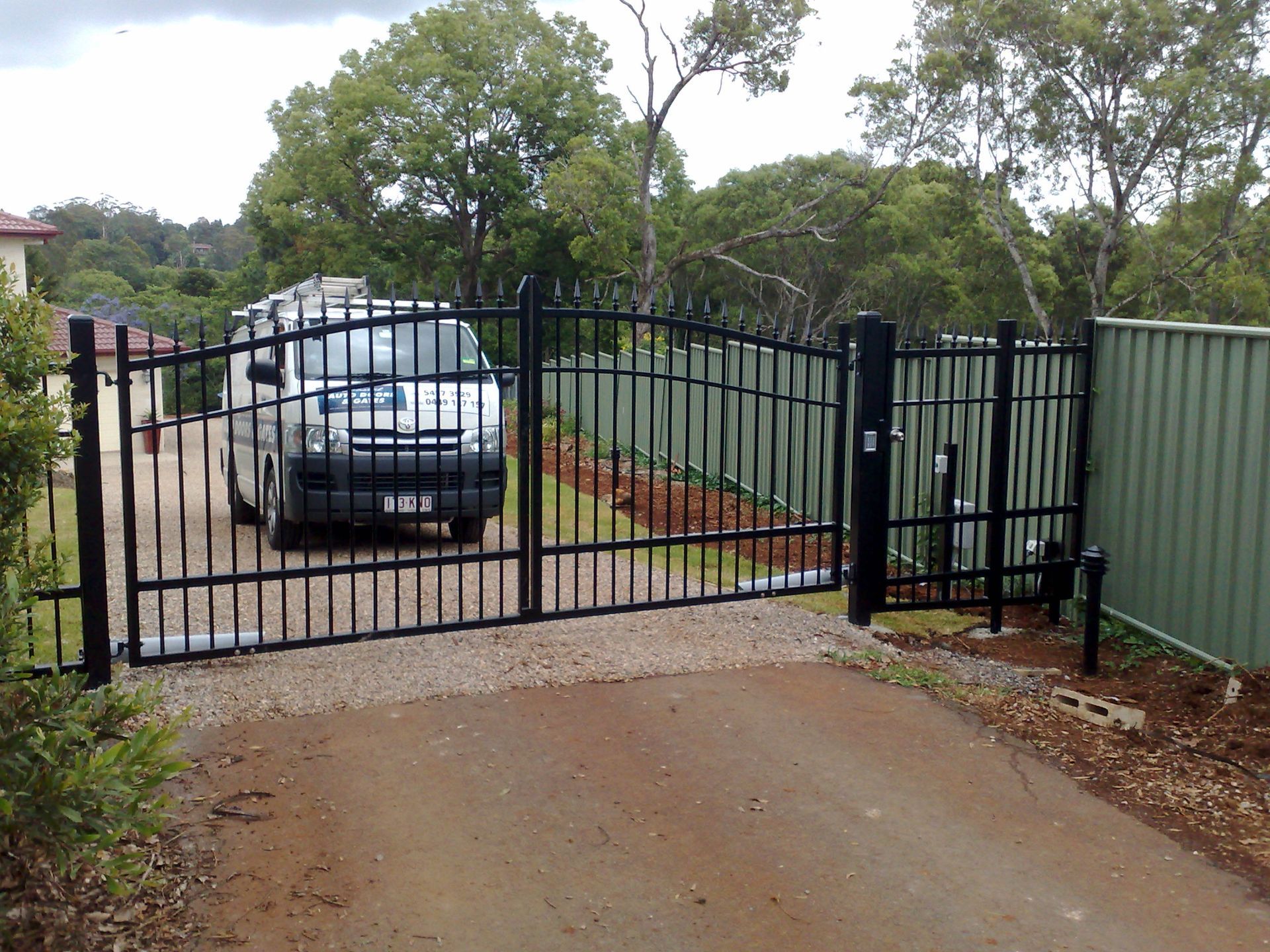 Black Metal Driveway Gate, Open, With a Van Parked Inside — Coastal Auto Doors & Gates In Buderim, QLD