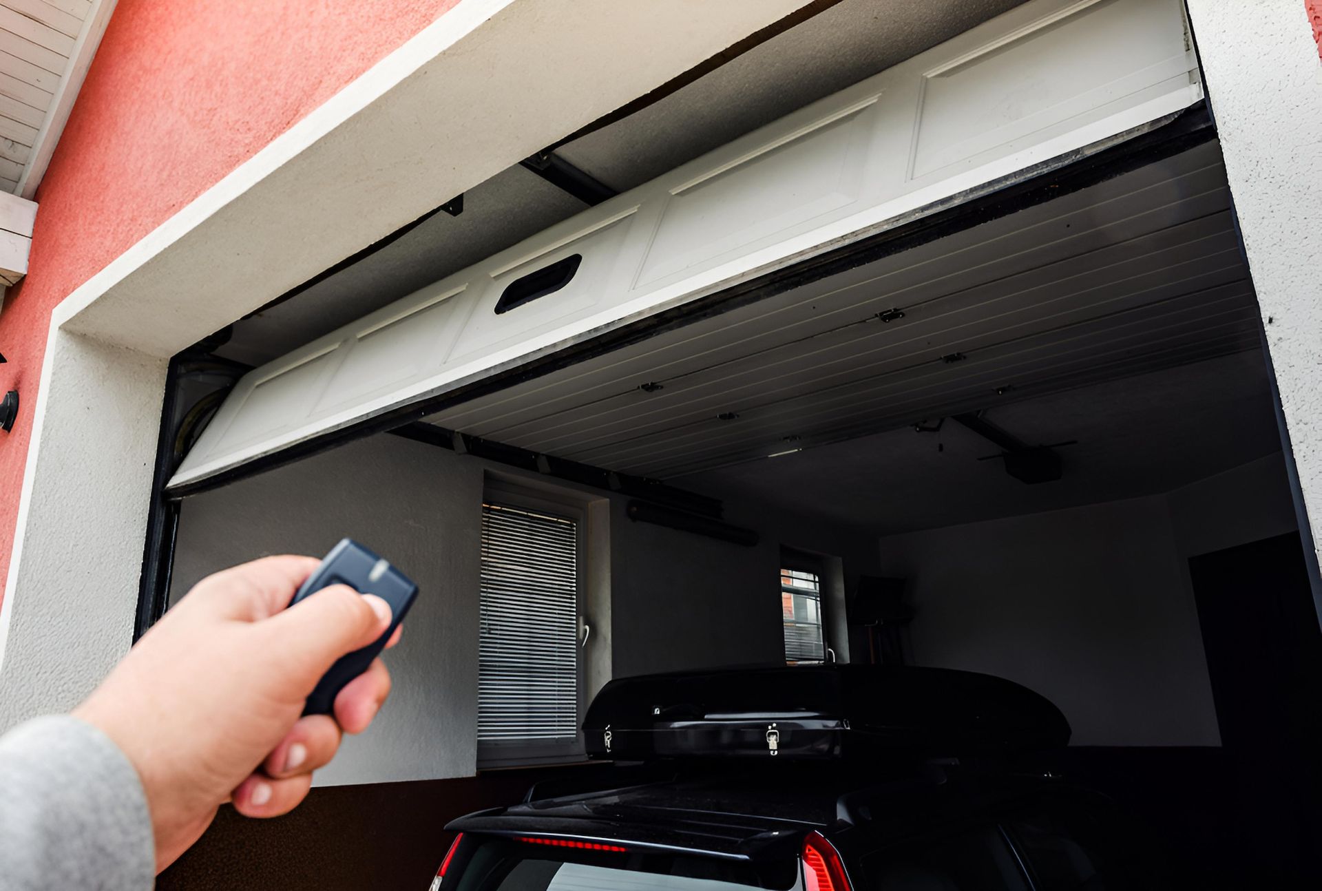 A Person Is Driving A Car And Using A Remote Control To Open A Garage Door — Coastal Auto Doors & Gates In Palmwoods, QLD