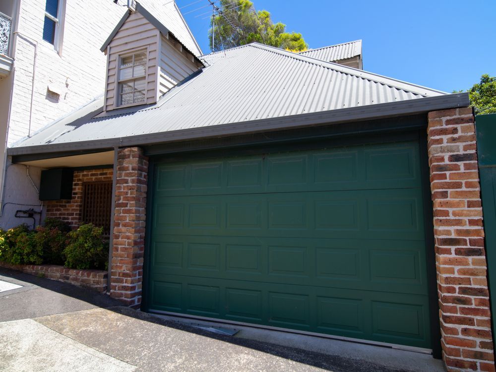 Brick House with A Dark Green Garage Door and Light Gray Roof — Coastal Auto Garage Doors & Gates In Narangba, QLD