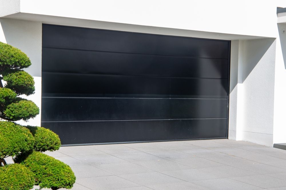 House With a Black Garage Door and Driveway — Coastal Auto Garage Doors & Gates In Caboolture, QLD