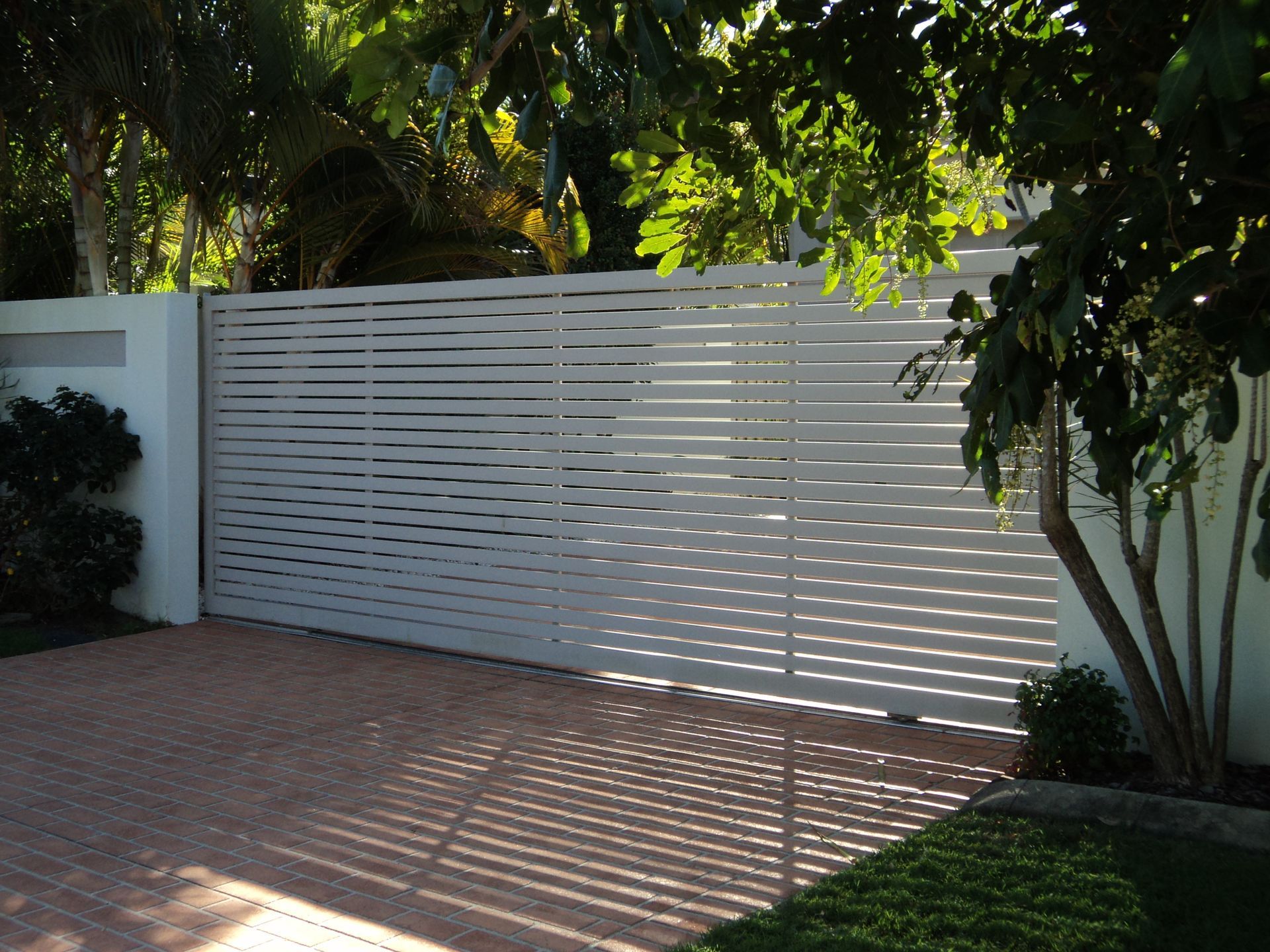 White Horizontal Slat Gate in Front of a Brick Driveway — Coastal Auto Doors & Gates In Nambour, QLD