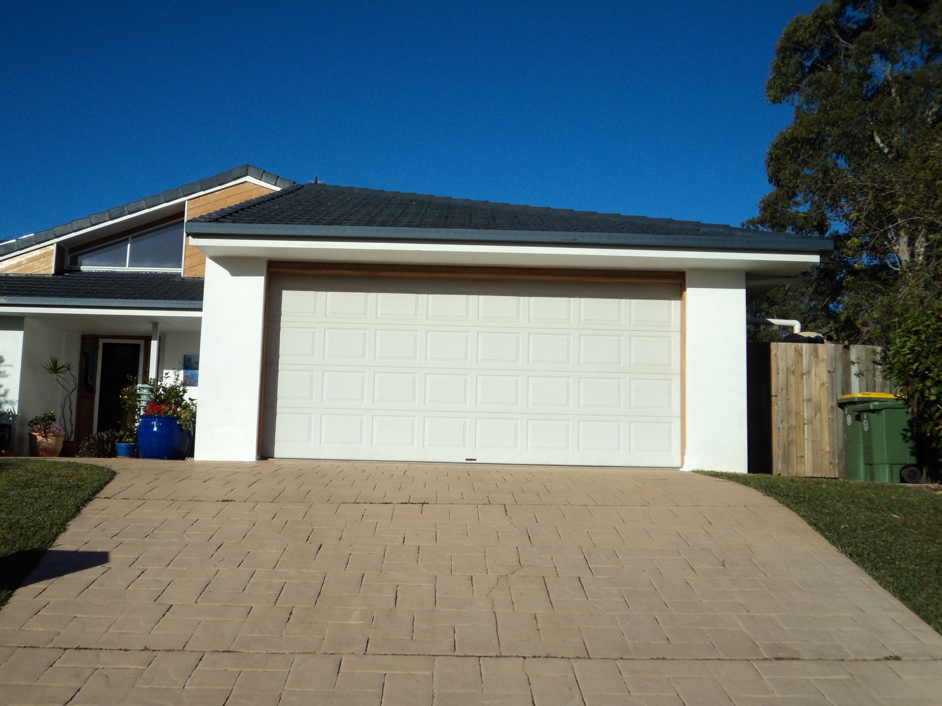 White Garage Door on a House With a Brick Driveway Under a Clear, Blue Sky — Coastal Auto Doors & Gates In Palmwoods, QLD