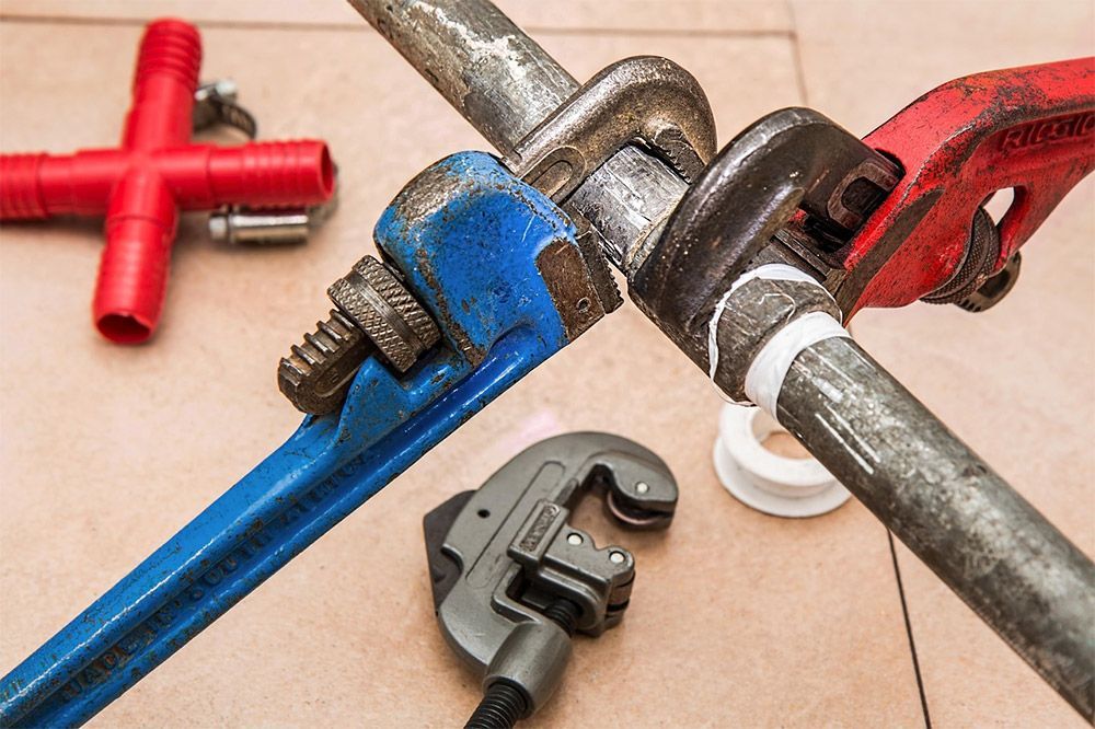 Plumbing tools on a tile floor representing water heater repair and installation in Denver