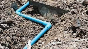 Blue plastic sewer pipe in a dirt trench — warning signs of sewer line failure in Denver