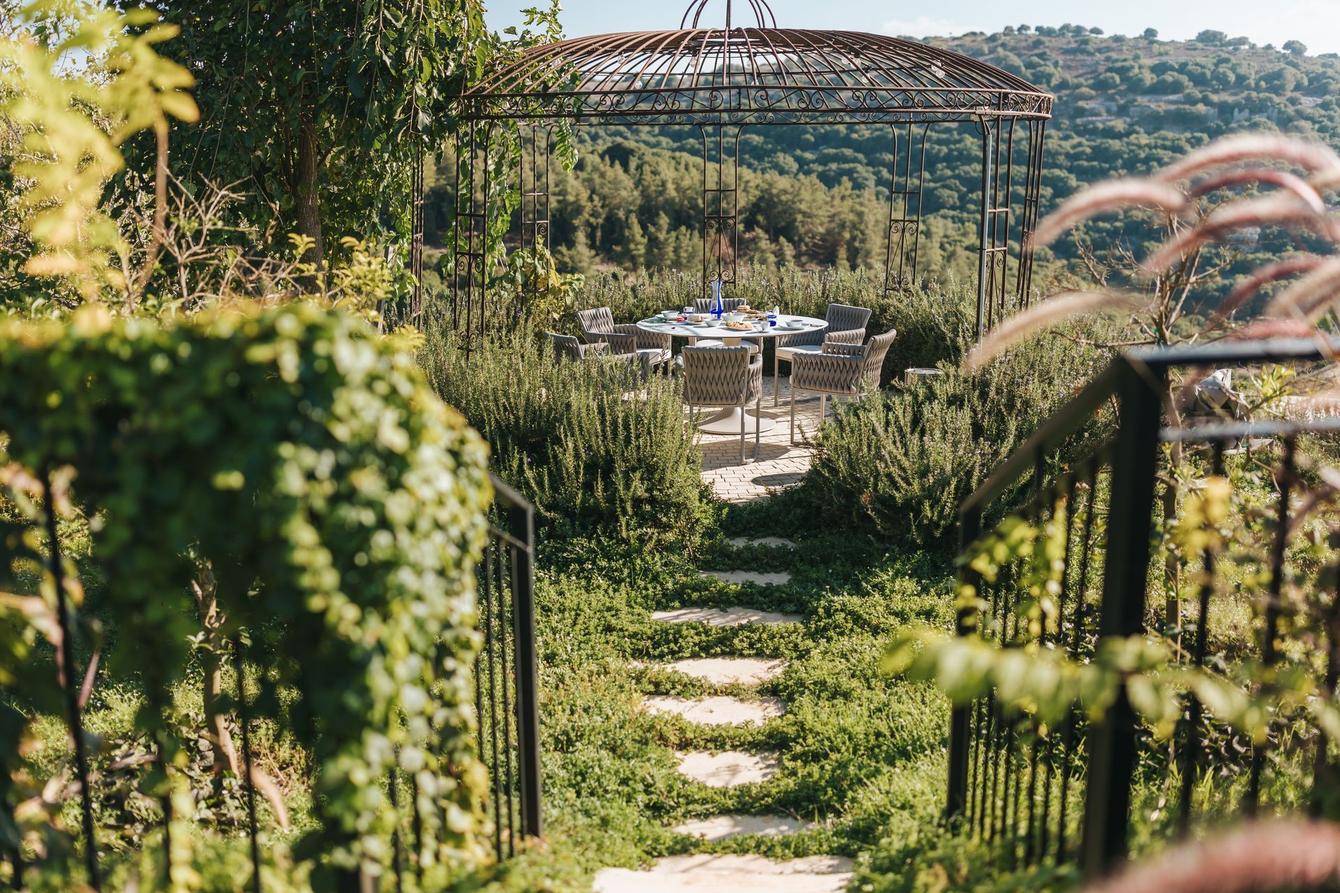 Stone steps lead to an outdoor dining table set beneath a canopy with a scenic view.