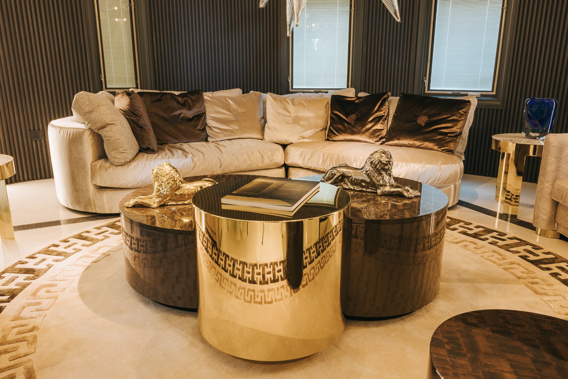 Luxurious living room with gold accents, beige sofa, and round coffee tables on a patterned rug.