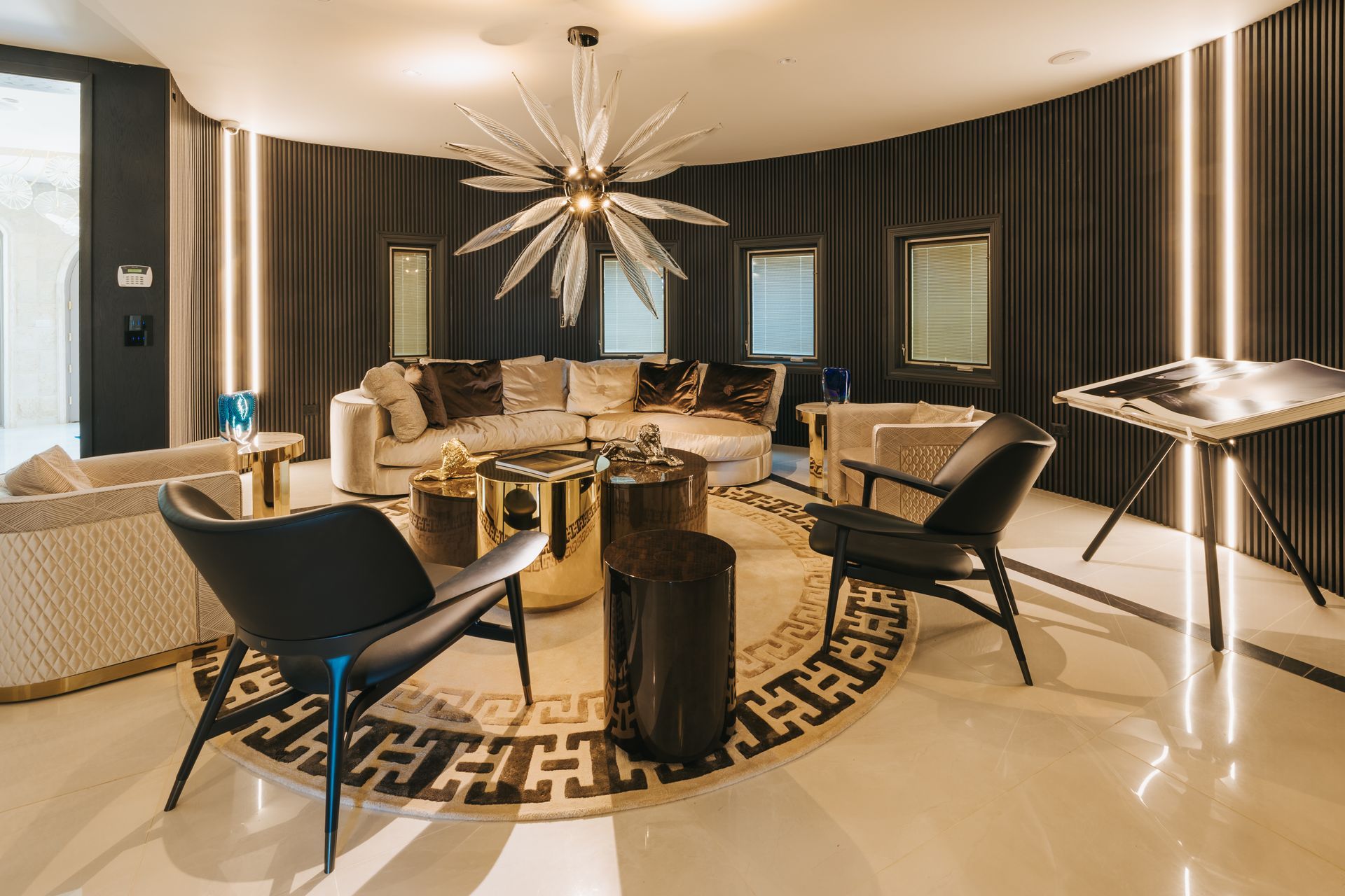 Living room with curved wall, gold accents, modern furniture, and a sunburst chandelier.