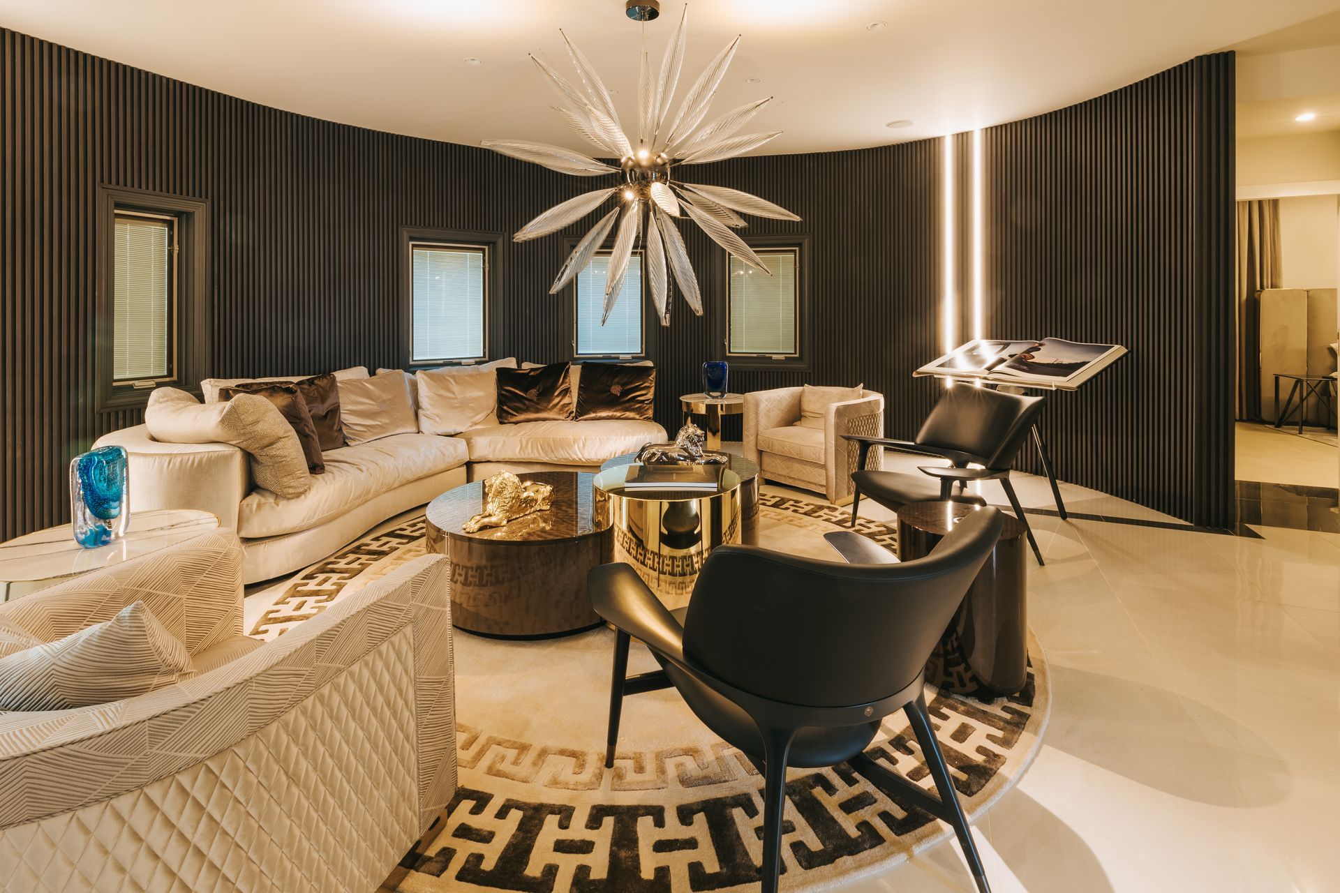 Luxurious living room with curved sofa, gold accents, and a starburst chandelier.