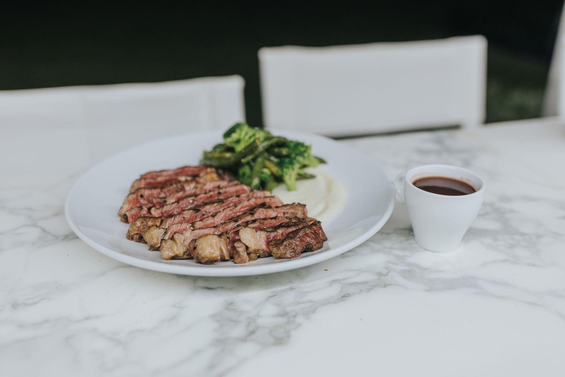 Sliced steak with mashed potatoes and asparagus, served with sauce.