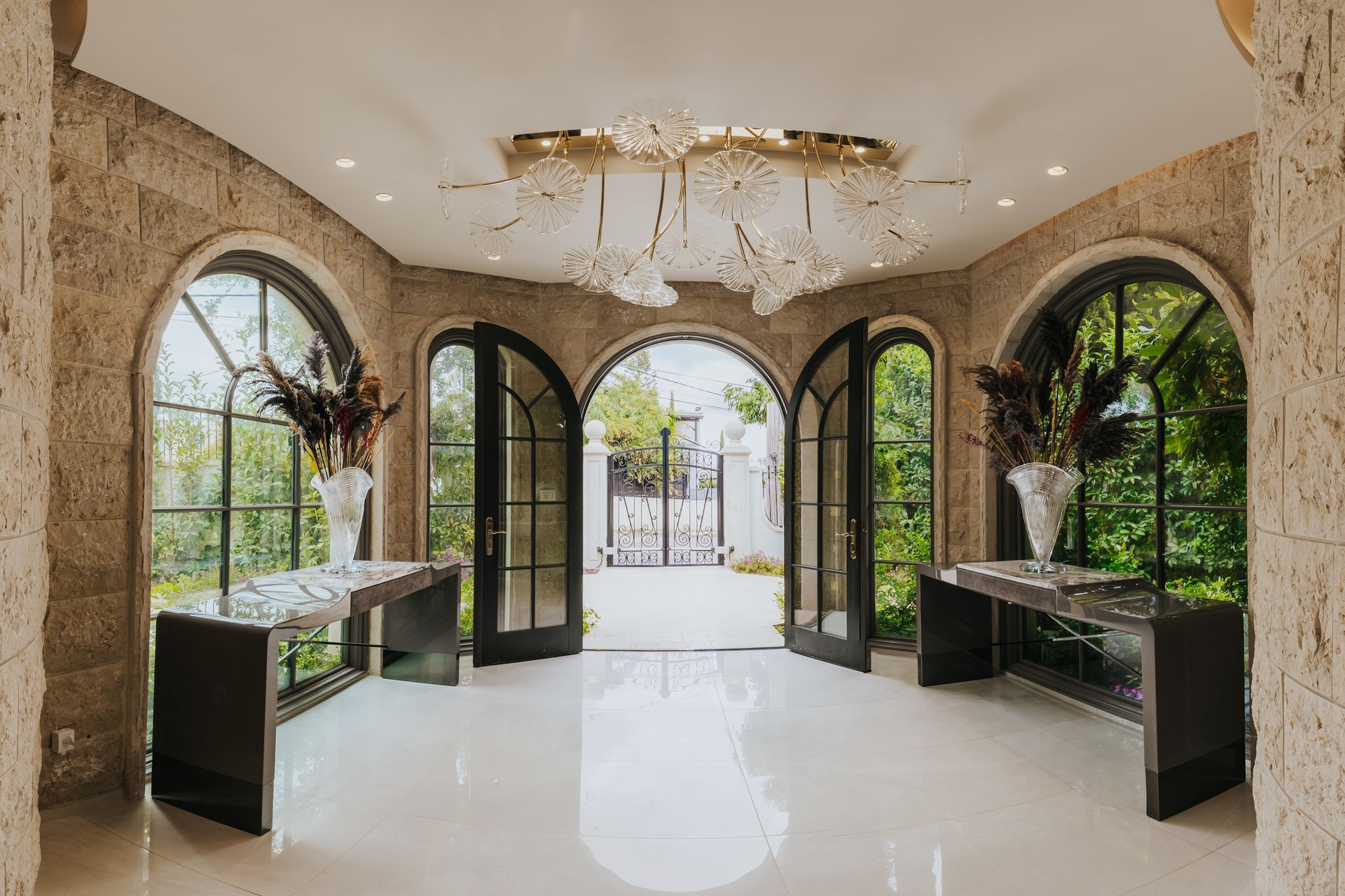 Elegant foyer with arched windows, doors, and a crystal chandelier.